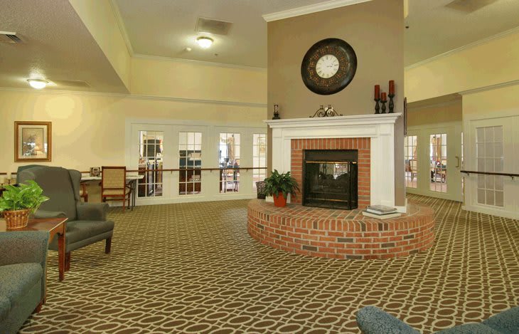 A cozy living room featuring a central fireplace with surrounding seating and elegant interior design.