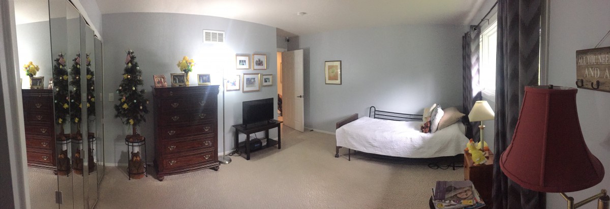 A neatly arranged bedroom featuring a bed, television, and wall art.