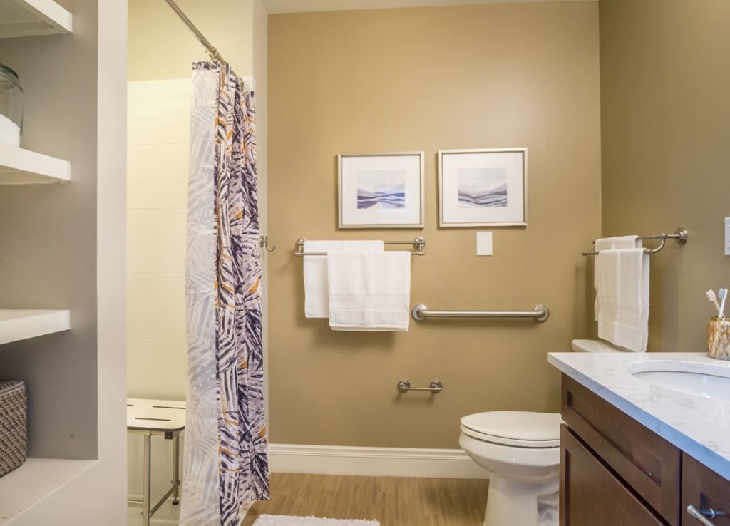 A clean and organized bathroom with a shower, toilet, and towel rack.