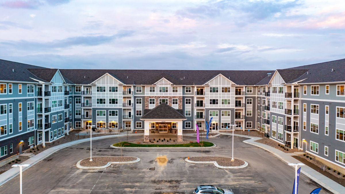 A large residential apartment building with a central entrance and surrounding parking area.