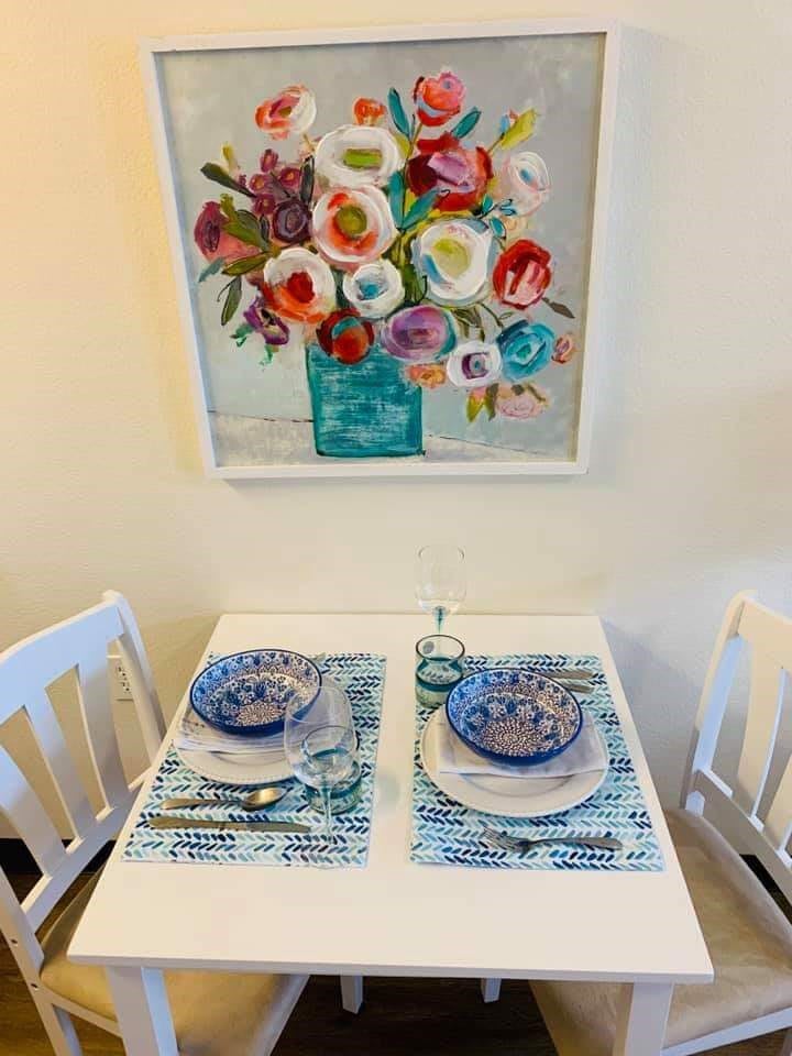 A cozy dining setup with colorful floral artwork and neatly arranged tableware.