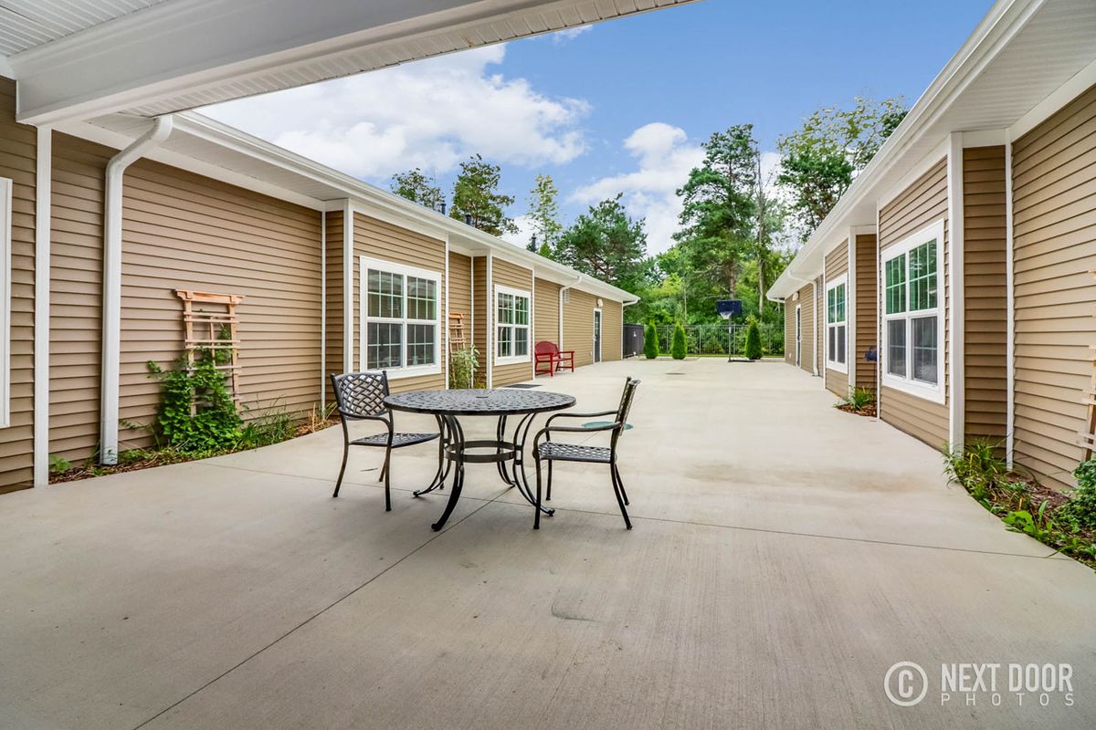A spacious courtyard with outdoor furniture surrounded by buildings and trees.