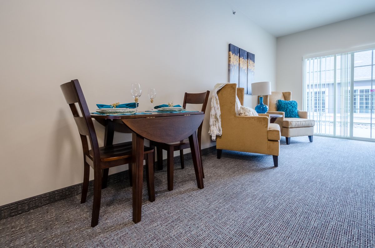 A cozy living space featuring a dining table and chairs, with comfortable seating in the background.