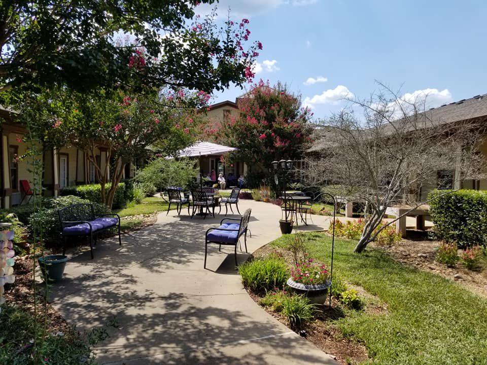 A serene garden with outdoor seating and lush greenery along a winding pathway.