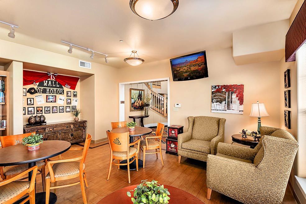 A cozy living room with comfortable seating, a television mounted on the wall, and warm lighting.