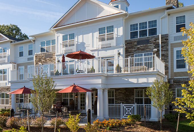 A modern residential building with balconies and red patio umbrellas.