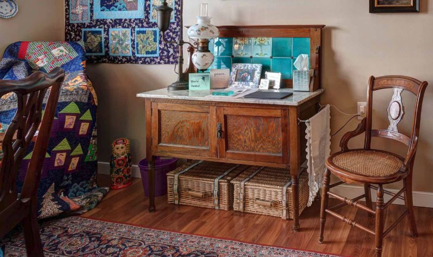 A cozy room featuring a vintage wooden sideboard adorned with decorative items and illuminated by a classic table lamp.