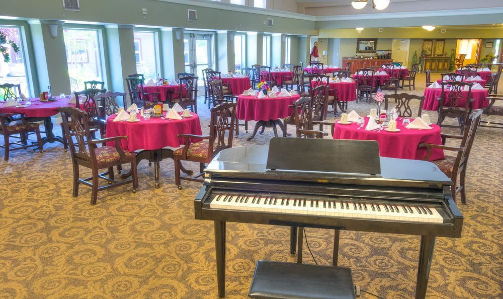 A dining area with elegantly set tables and a piano in the foreground.