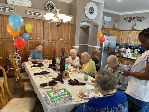 A joyful birthday celebration with friends and family gathered around the dining table.