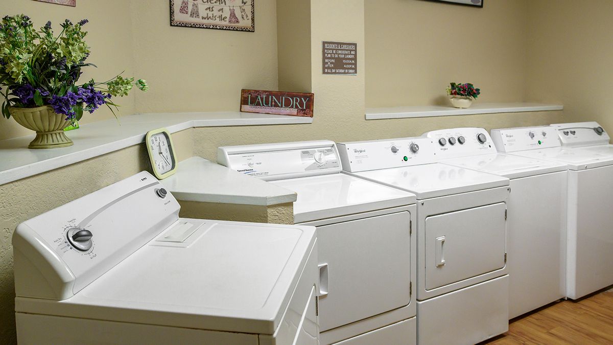 A clean and organized laundry room with several washing machines and dryers.