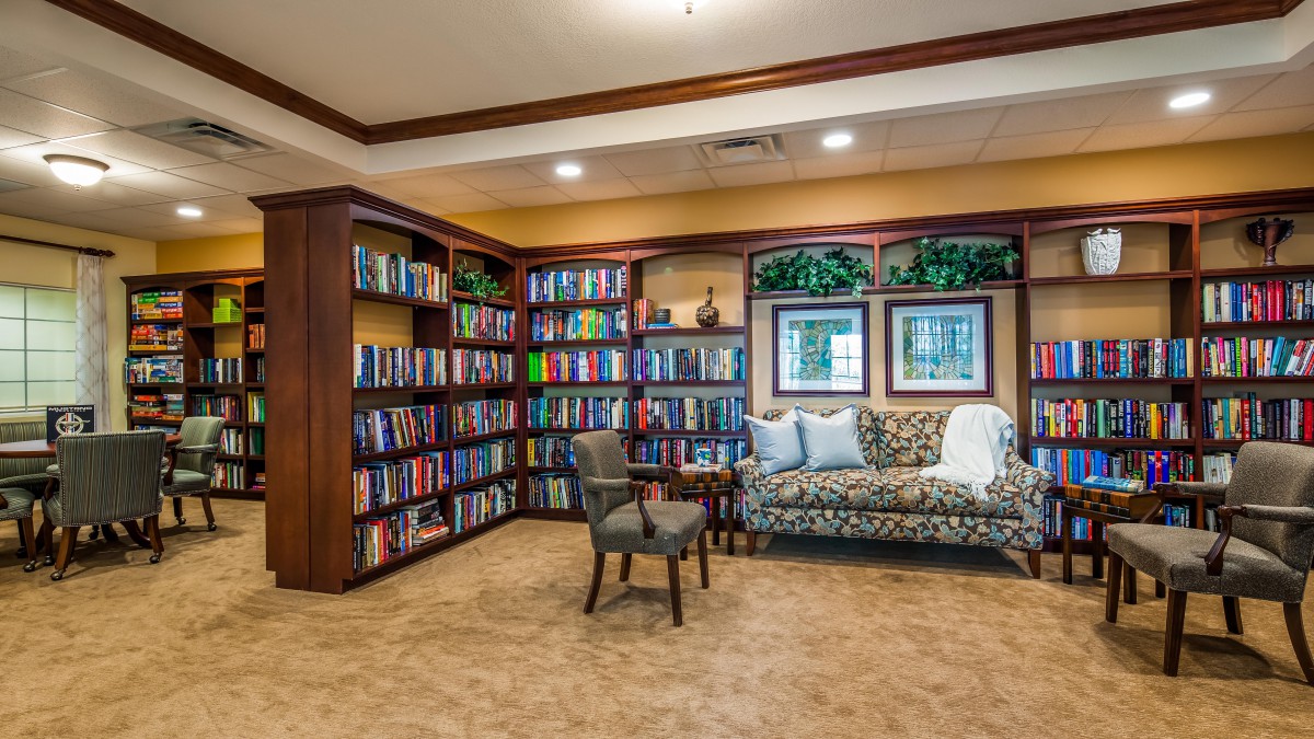A cozy library corner featuring a sofa, chair, and extensive bookshelves.