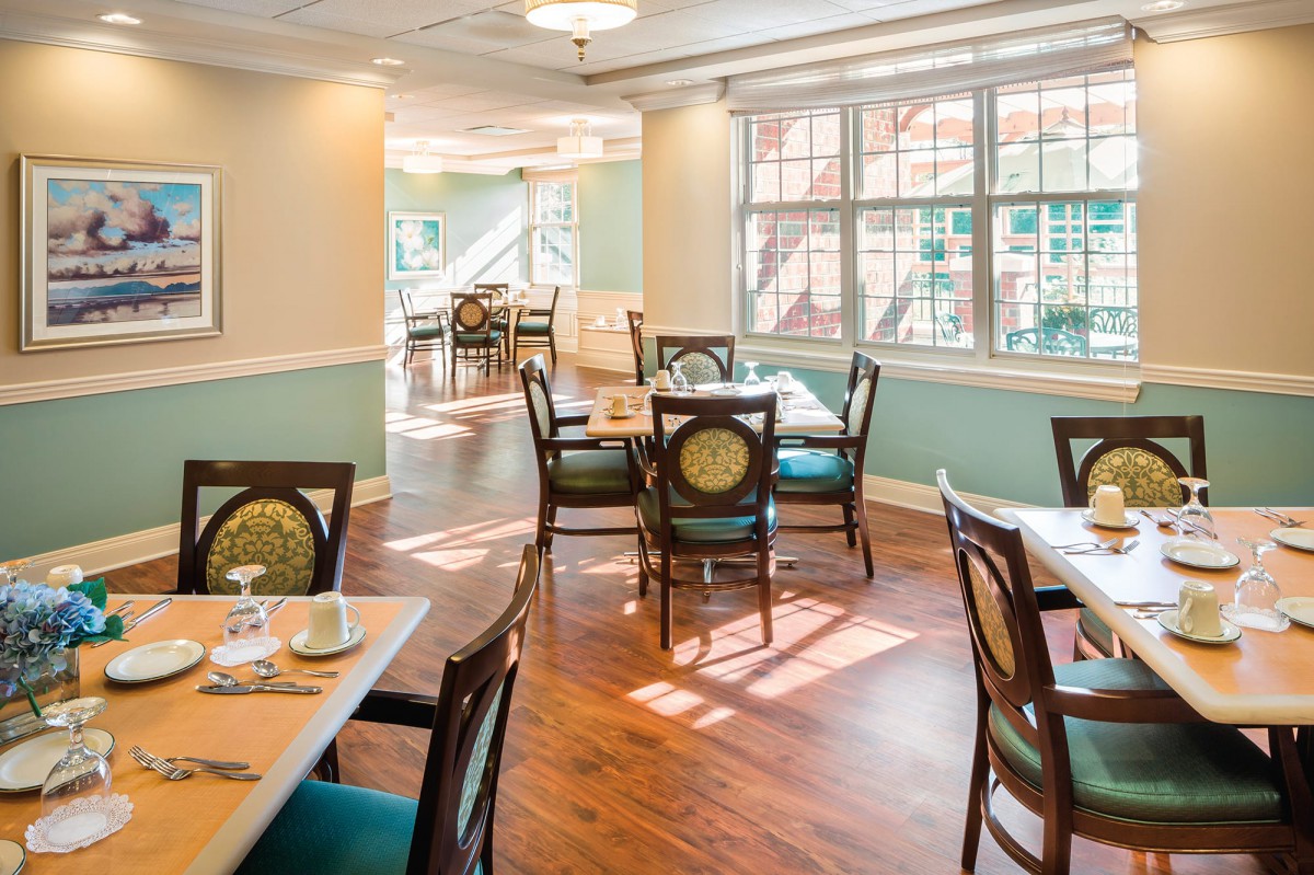 A well-lit dining area with neatly arranged tables and chairs, featuring large windows that allow ample natural light to fill the space.