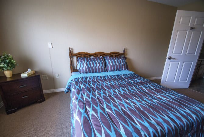 A neatly arranged bedroom with a patterned bedspread and pillows.