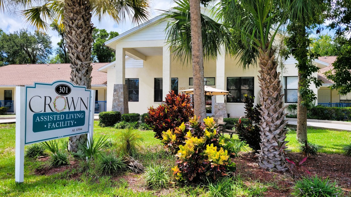 A beautiful house surrounded by palm trees and lush landscaping on a sunny day.