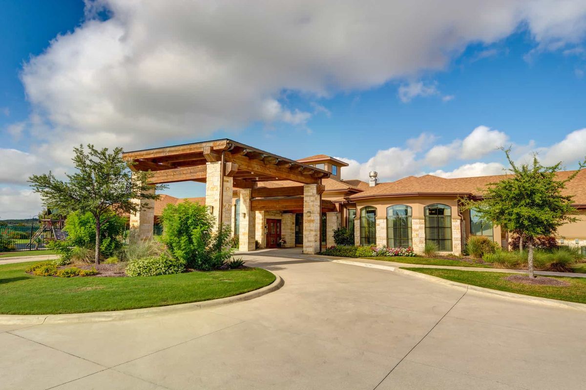 A beautiful luxury home with a large driveway and manicured landscaping under a blue sky.