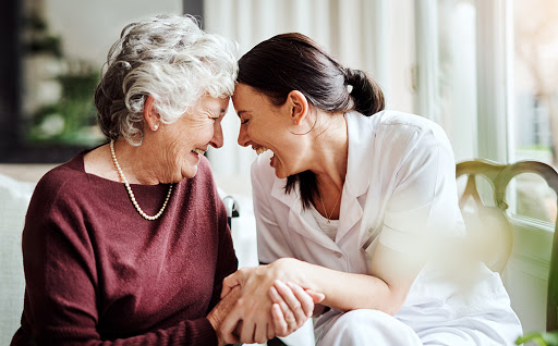 A heartfelt moment shared between an elderly woman and her caregiver, filled with laughter and connection.