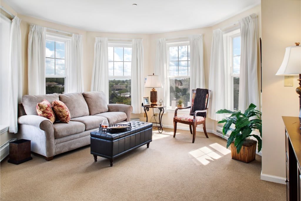 A cozy living room with a sofa, an armchair, and large windows letting in natural light.