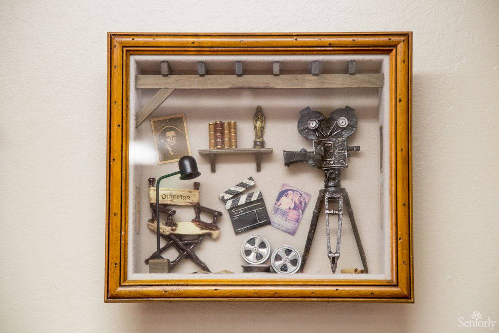 A shadow box display featuring vintage film memorabilia including a camera, director's chair, clapperboard, and film reels.