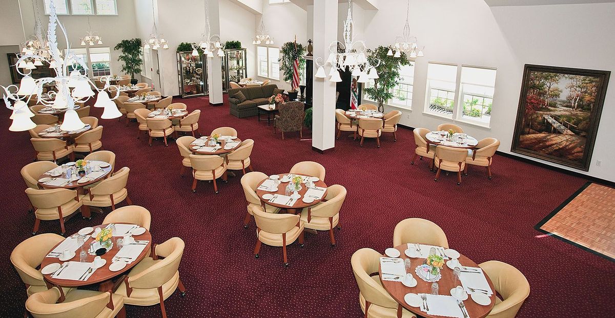 An elegant dining area with neatly arranged tables and chairs on a vibrant red carpet.