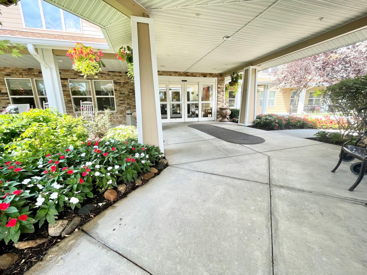 A welcoming building entrance with a covered walkway and a vibrant flower bed.