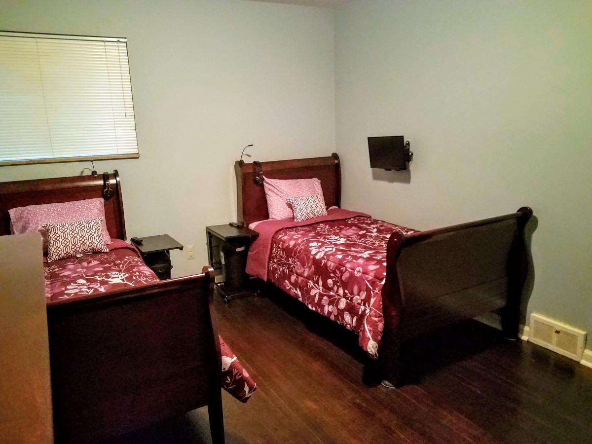 A cozy bedroom with two twin beds featuring red floral bedding and wooden furniture.