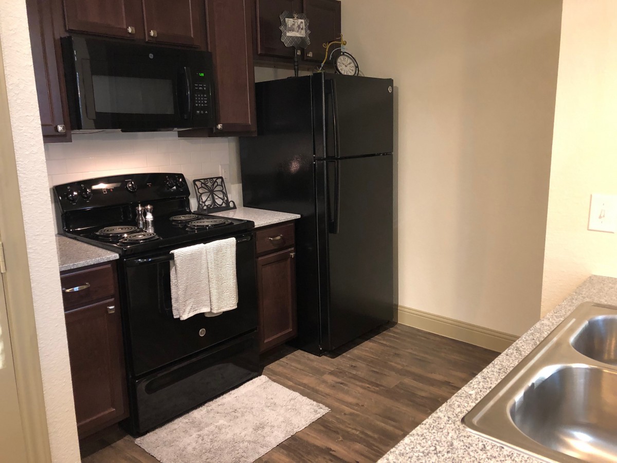 A modern kitchen with black appliances and wooden cabinets.