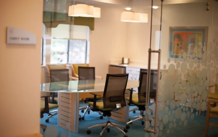 A modern conference room with a glass table, office chairs, and a well-lit atmosphere.