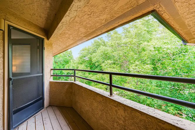 A quiet balcony overlooking lush green trees.