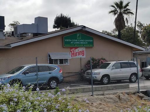 A building displaying a 'Hiring' sign, surrounded by cars and palm trees.