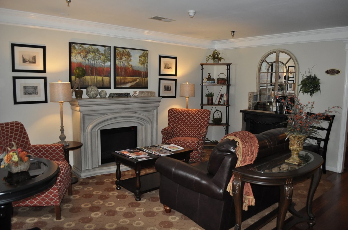 A cozy living room featuring a fireplace, armchairs, and decorative artwork.