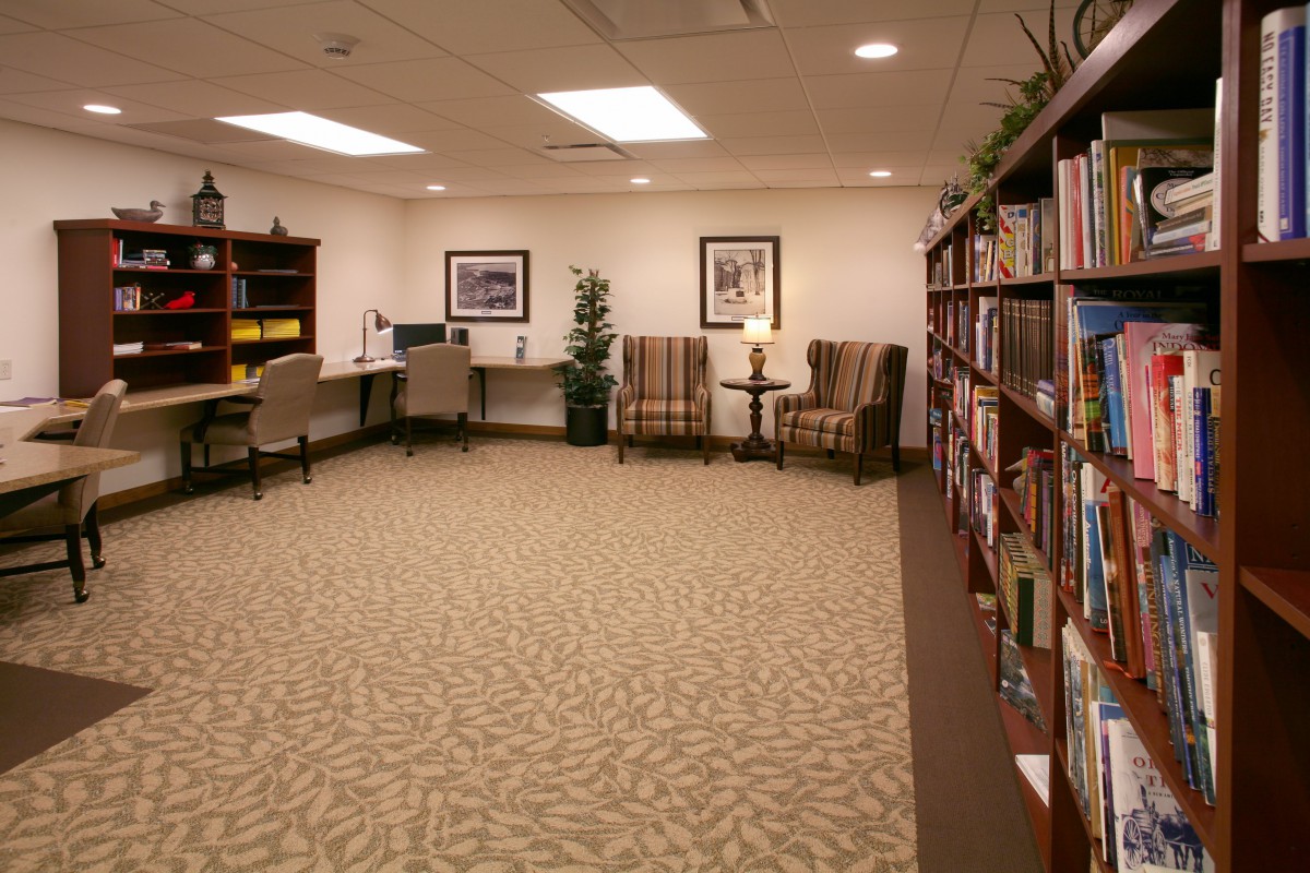 A quiet library space with bookshelves, chairs, and a computer desk.