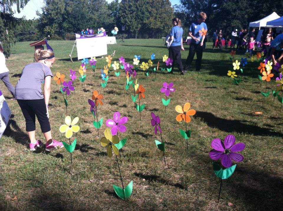 People enjoy a sunny day in the park, surrounded by colorful artificial flowers planted in the grass.