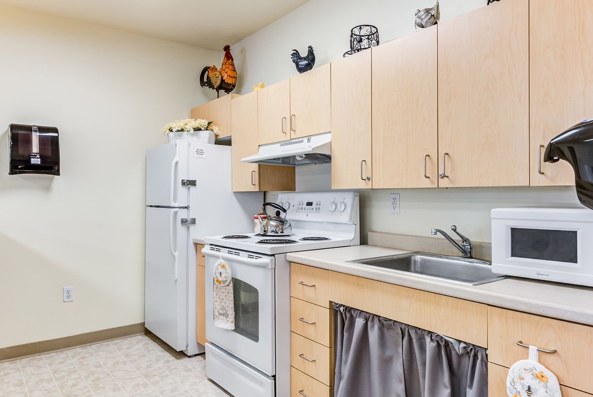A modern kitchen with light wood cabinets, a white refrigerator, and an electric stove.