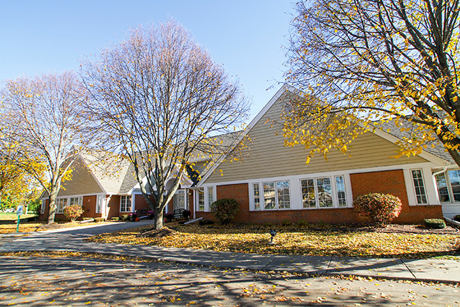 A suburban house surrounded by trees in autumn.