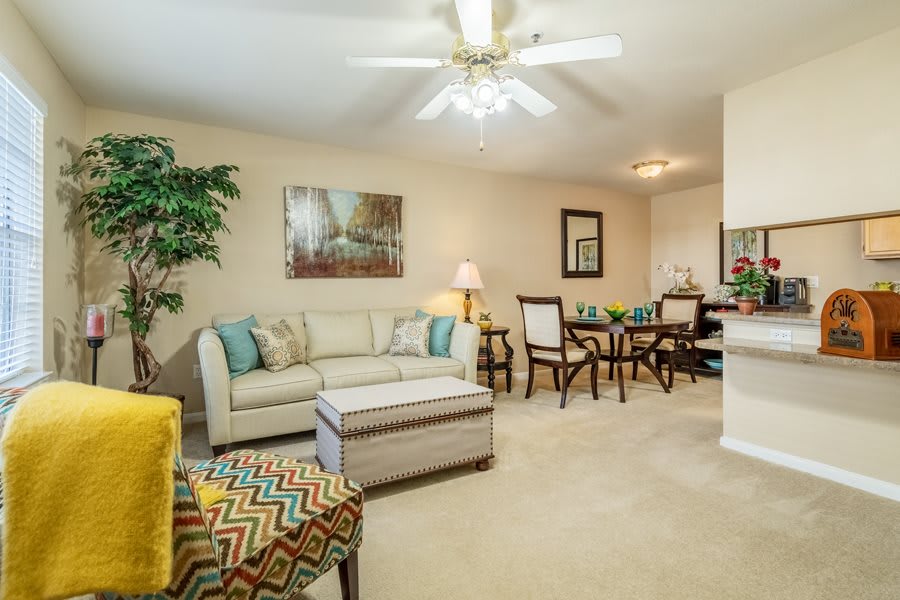 A cozy living room featuring a sofa, coffee table, ceiling fan, and decorative elements.