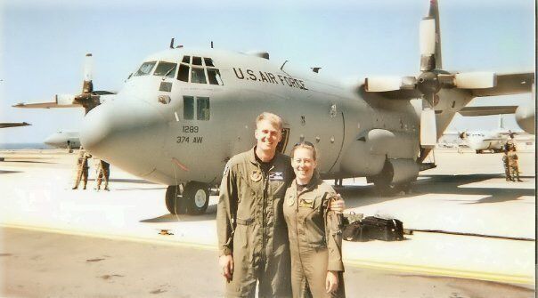 Two US Air Force personnel stand in front of a C-130 Hercules aircraft.