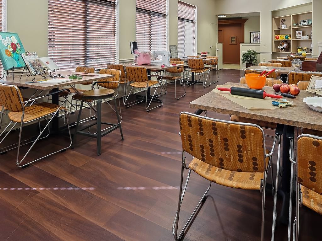 A well-lit classroom with tables and chairs arranged neatly on a wooden floor.