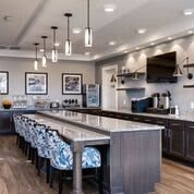 A modern kitchen featuring a large island with bar stools, pendant lighting, and sleek appliances.