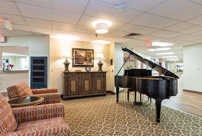 A spacious lobby with a grand piano, elegant furniture, and warm lighting.