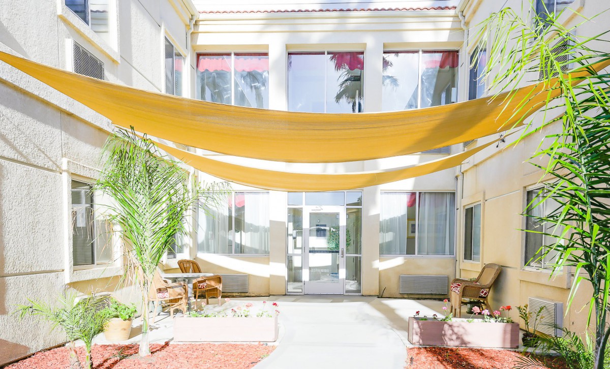A bright courtyard featuring shade sails and comfortable outdoor seating.