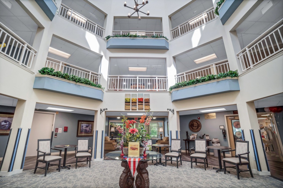 A spacious atrium with multiple balconies, featuring a modern seating area and decorative plants.