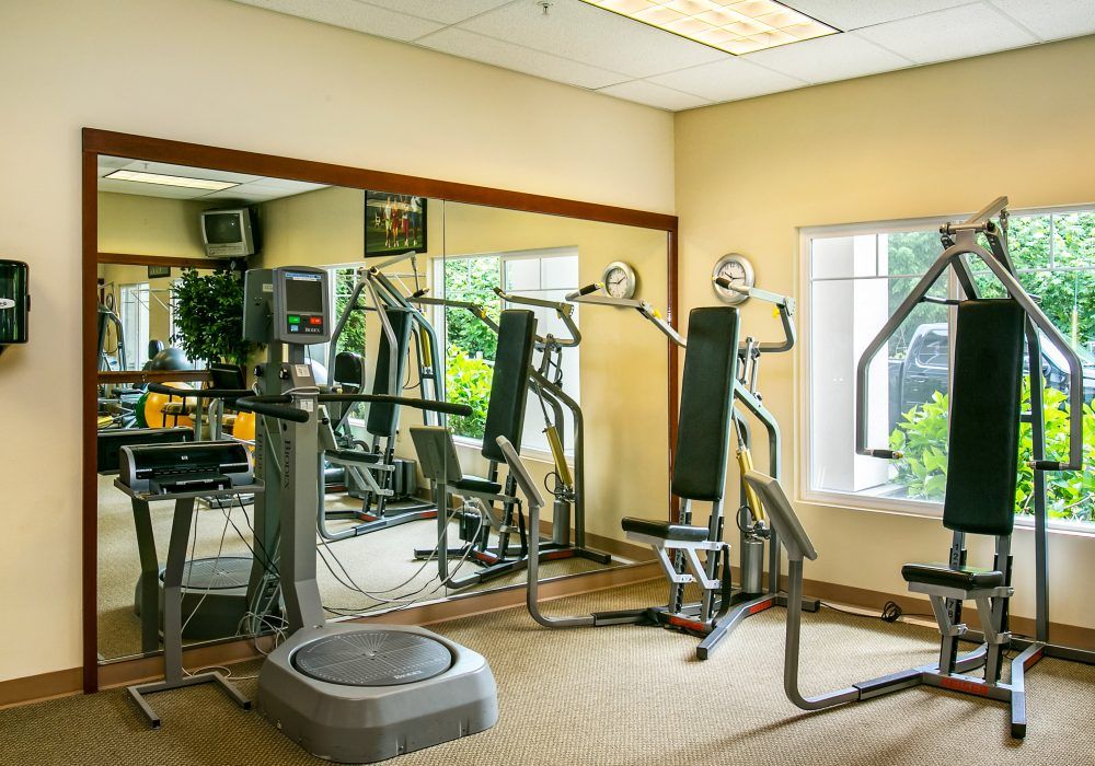 A well-equipped gym with various exercise machines and mirrors.