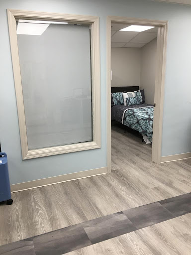 A view of a cozy bedroom with floral bedding, seen through a glass partition.