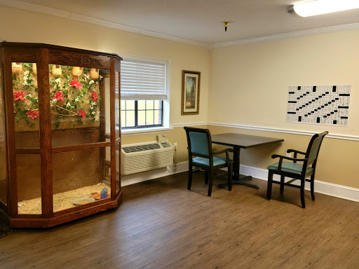 A cozy interior of a room featuring a table, chairs, and a display case with decorative items.