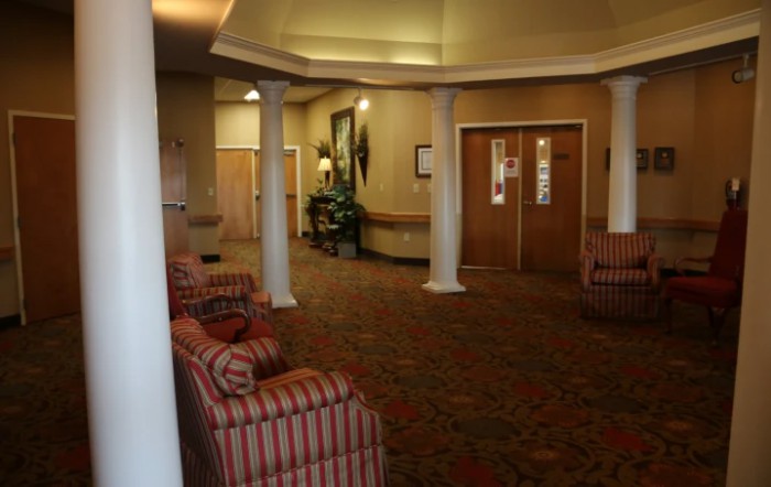A well-lit lobby with striped armchairs, columns, and a patterned carpet.