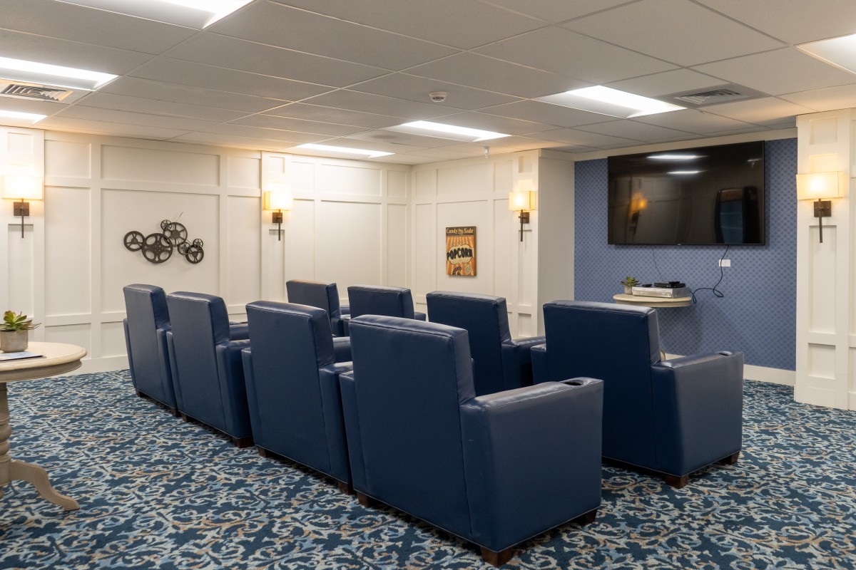A cozy theater room with comfortable seating and a large TV screen.