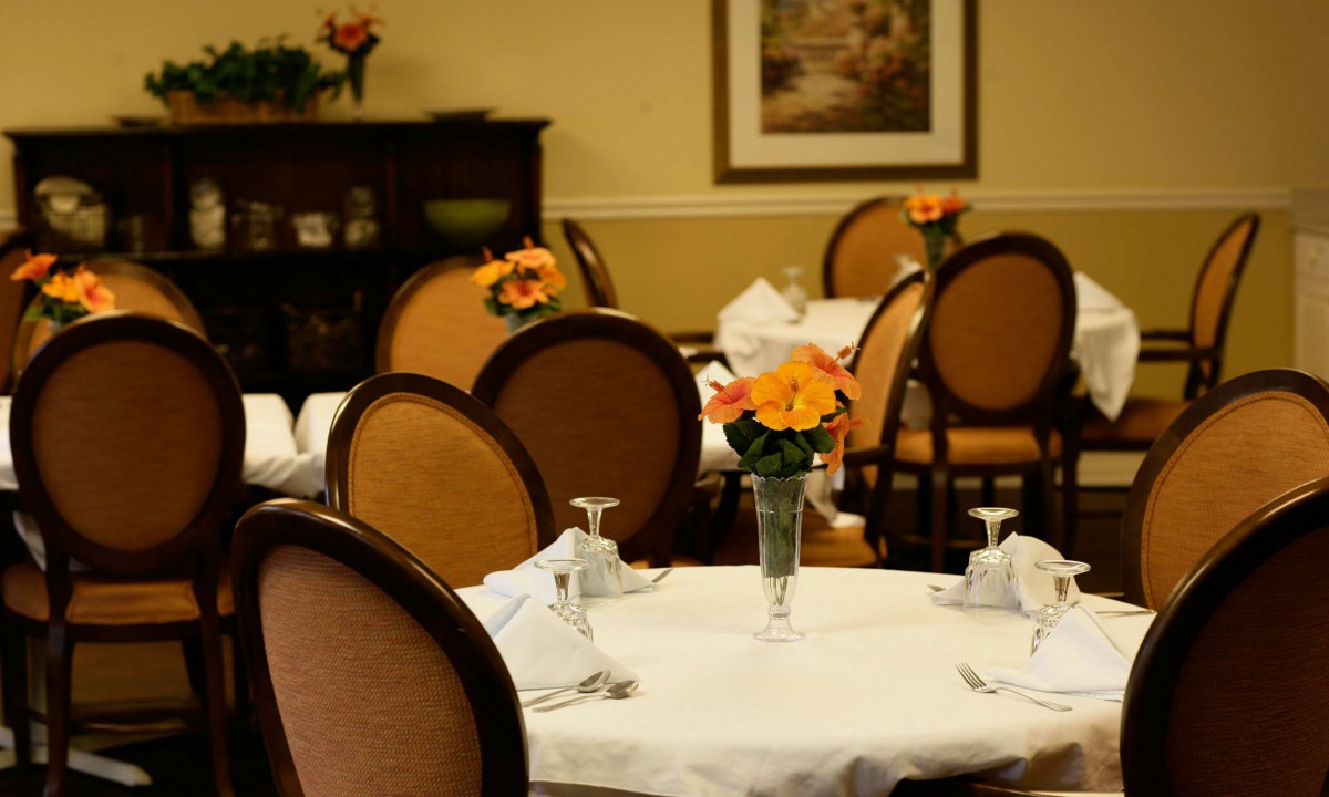 A cozy restaurant dining area with elegantly set tables and floral decorations.