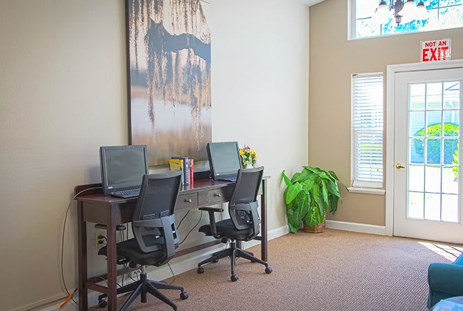 A small office workspace with computers and chairs by the window.