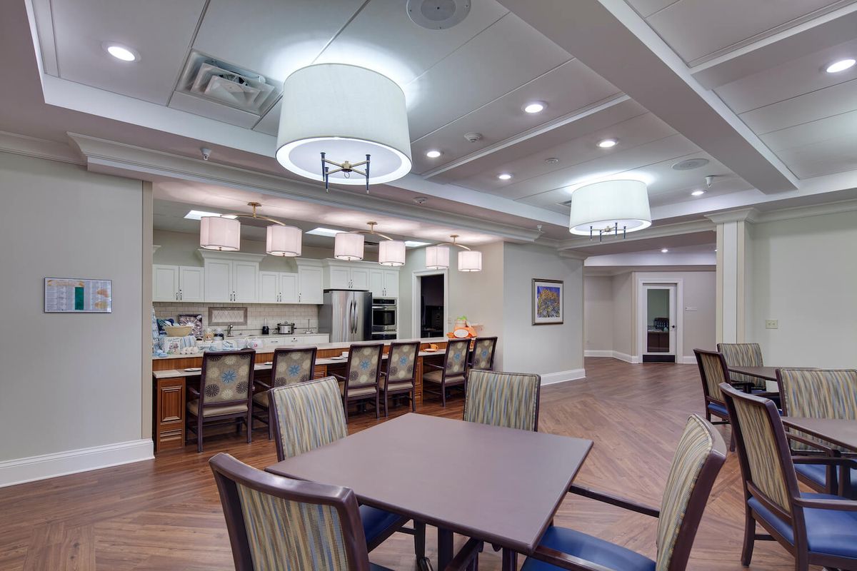 A modern communal kitchen and dining space with elegant lighting and wood flooring.