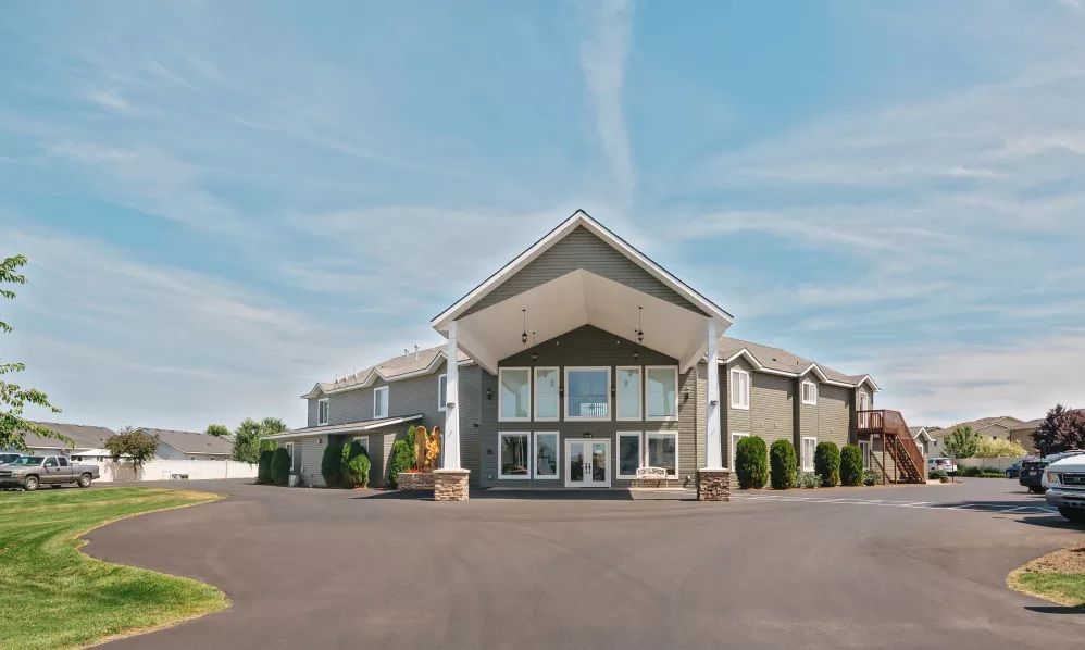 A modern hotel building with a spacious driveway under a clear sky.